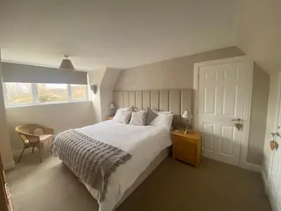 a bedroom with a large white bed and a window at Four Woodside in Craighouse