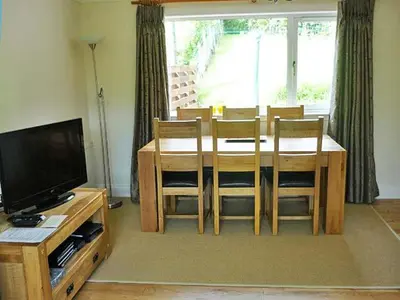 a living room with a dining table and a television at Four Woodside in Craighouse