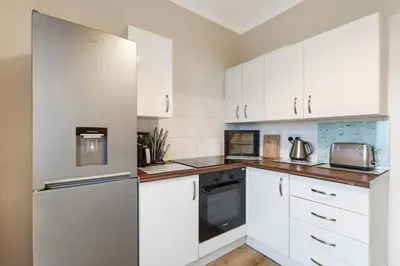 a white kitchen with white cabinets and appliances at Free Parking - Central - Sleeps 6 - Great Location in Armadale