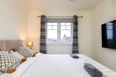 a bedroom with a large white bed with a window at 4 Bedroom Townhouse In Stirling in Stirling