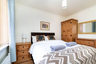 a bedroom with a bed and a wooden dresser at 4 Bedroom Townhouse In Stirling in Stirling