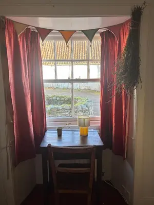 a table in front of a window with red curtains at Ivy Cottage in Causewayhead