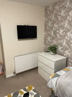 a bedroom with a flat screen tv on the wall at Spacious two bedroom flat, entire property in Greenock