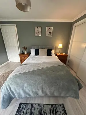a bedroom with a large bed with a gray blanket at Cosy Glasgow Barrowlands stay-spacious & free parking in Glasgow