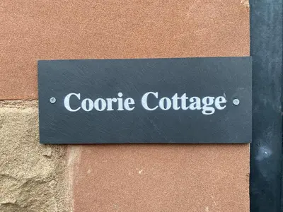 a sign for a corporate office on the side of a building at Coorie Cottage in Edinburgh