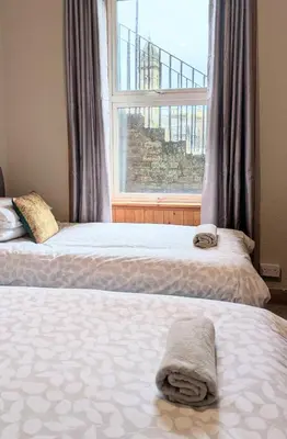 two beds in front of a window with towels on them at Kintyre apartment in Campbeltown