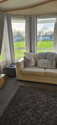 a living room with a couch and two windows at Montrose No3 - Turnberry Holiday Park in Turnberry
