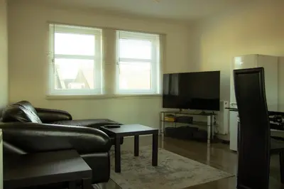 a living room with a leather couch and a television at 3 bedroom luxury Apartment in Prestwick