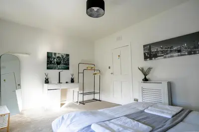 a white bedroom with a bed and a desk at Caldwell House in Glasgow