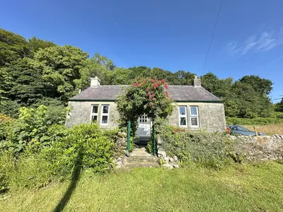 a house with areath of flowers on the front of it at Dunmore Cottage in Tarbert