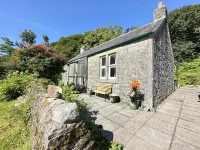 a stone building with a bench in front of it at Dunmore Cottage in Tarbert