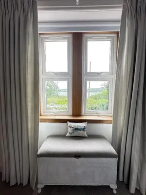 a window seat in a room with two windows at Dunmore Cottage in Tarbert