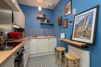 a kitchen with blue walls and a counter and stools at Andy's Pad in Edinburgh