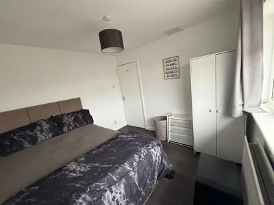 a bedroom with a bed and a dresser and a window at Private Room in Berkhamsted high street in Moffat