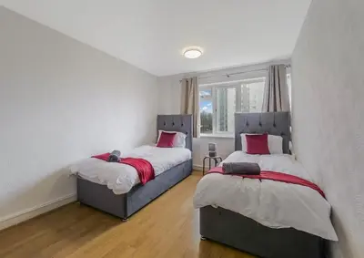two twin beds in a bedroom with white walls at Free Parking - 3 Bedrooms - Sleeps 7 - Airport in Paisley