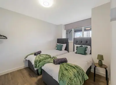 two beds in a room with white walls at Free Parking - 3 Bedrooms - Sleeps 7 - Airport in Paisley