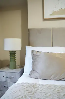 a bedroom with a bed with a lamp on a night stand at Neilston Gateaway in Paisley