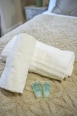 a towel on a bed with two bottles of soap at Neilston Gateaway in Paisley