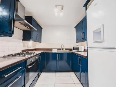 a kitchen with blue cabinets and a white refrigerator at Modern 2-Bed Near Braehead in Renfrew