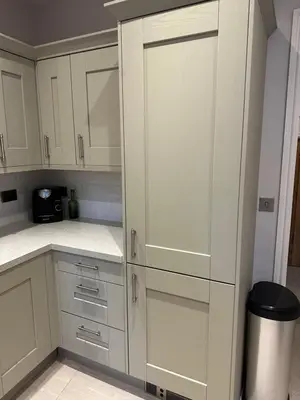 a white kitchen with white cabinets and a trash can at The Oldest House Located in the heart of Matlock in Moffat