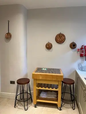 a kitchen with two stools and a table with a counter at The Oldest House Located in the heart of Matlock in Moffat
