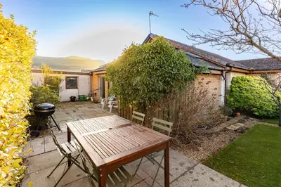 a patio with a wooden table and chairs in a garden at Bright, spacious house in Edinburgh