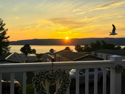 a bird flying over a balcony with a sunset at Wemyss Bay Seaview Sanctuary in Wemyss Bay