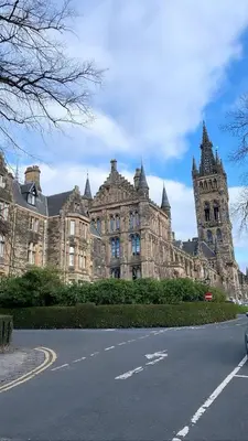 a large stone building with a clock tower on a street at FREE Pool Table Cinema Room TableTennis AirHockey Glasgow City in Glasgow