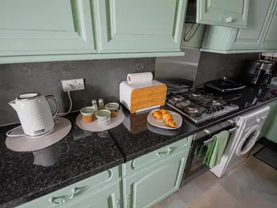 a kitchen with green cabinets and a counter top with a stove at FREE Pool Table Cinema Room TableTennis AirHockey Glasgow City in Glasgow