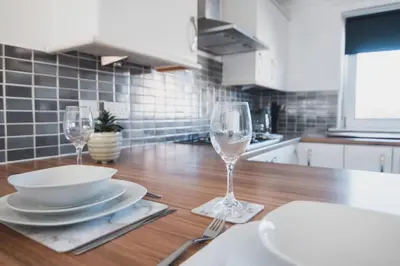 a wooden table with two wine glasses and plates on it at Modern 3BR Flat with Parking in Renfrew