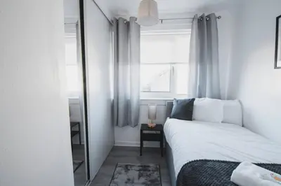 a small bedroom with a bed and a mirror at Modern 3BR Flat with Parking in Renfrew