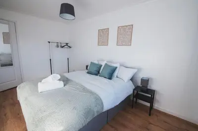 a white bedroom with a bed with blue pillows at Modern 3BR Flat with Parking in Renfrew