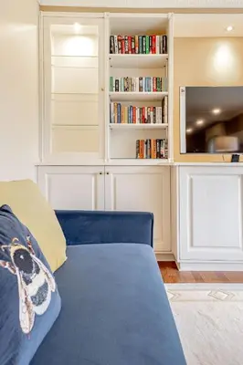 a living room with a blue couch and bookshelves at Spacious Gleneagles Apartment