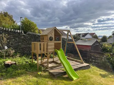 a playground with a slide and a house at Carmona Bank in Dunoon