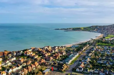 an aerial view of a beach with houses and the ocean at Beach Stroll Retreat, Swanage, Dorset in Moffat