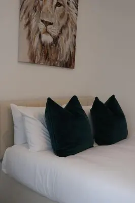 a bed with black pillows and a painting of a lion at Elegant 3BR Apt at Haymarket in Edinburgh