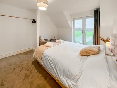 a white bedroom with a large bed and a window at Eriska View in Port Appin