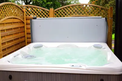 a hot tub on a patio with two chairs at Inglewood House and Spa in Alloa