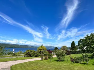 a pathway leading to a park with a view of the water at Oaktree Cottage, overlooking Loch Fyne in Cairndow
