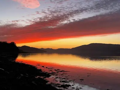 a sunset over a body of water with mountains at Oaktree Cottage, overlooking Loch Fyne in Cairndow