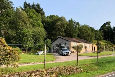 a house with a van parked in front of it at Oaktree Cottage, overlooking Loch Fyne in Cairndow