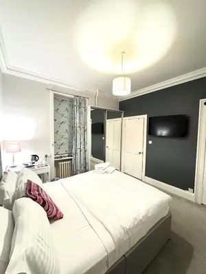 a bedroom with a large white bed and a tv at West Coates Mansion in Edinburgh