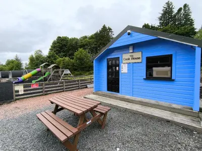 a blue building with a bench and a playground at Barrhill Holiday Park - Glamping in South West Scotland - Stinchar in Girvan