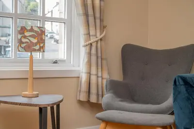 a living room with a chair and a window at Bow Apartment in Stirling