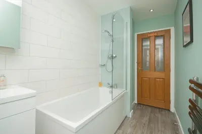 a bathroom with a tub and a shower with a glass door at Bow Apartment in Stirling