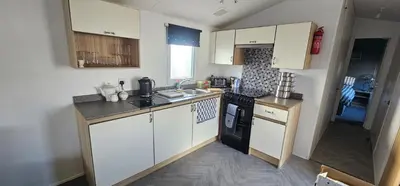 a kitchen with white cabinets and a stove top oven at Terri Towers in Stevenston