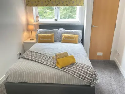 a bedroom with a bed with two pillows on it at Paisley Central Apartment in Paisley
