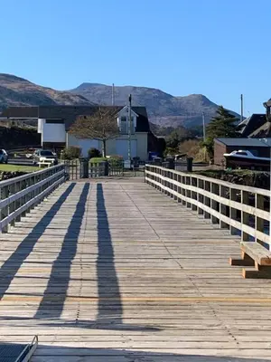 a wooden boardwalk with a long shadow on it at Salen Pier Haven in Salen