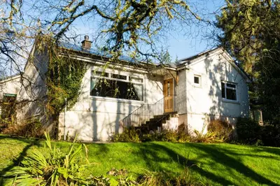 a white house with a porch and a yard at Westwood in Oban