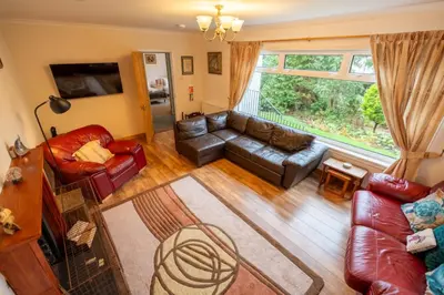 a living room with leather furniture and a large window at Westwood in Oban